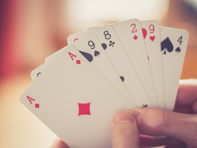 A person holding a hand's worth of various valued face cards in a game of Presidents and Assholes