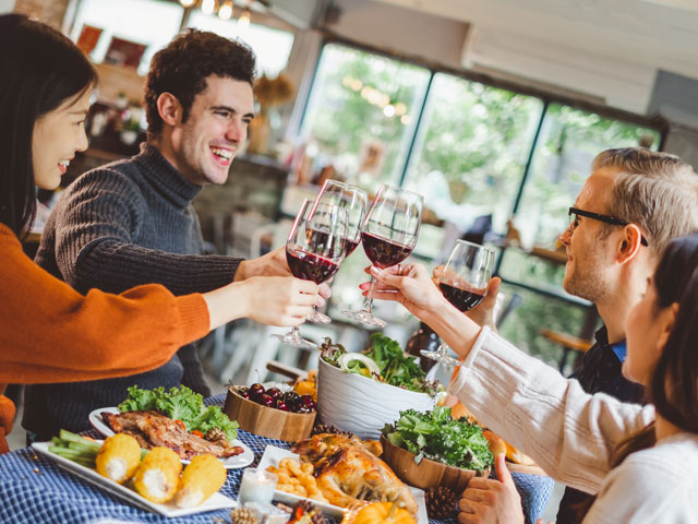 Four people celebrating the Thanksgiving Day Drinking Game with a Social by clinking their wine glasses