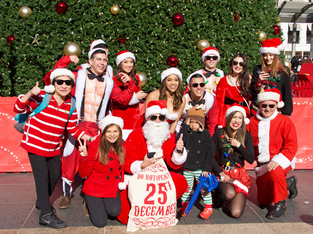 A group of festive people posing for a photo during the Santa Pub Crawl